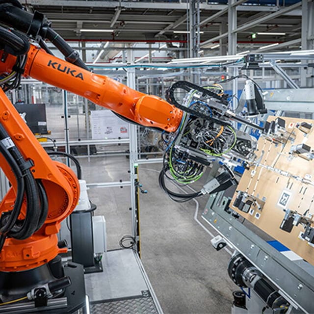 Industrial robot arm handling a wiring assembly
